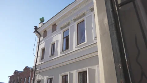 Building with damaged plaster facade rises against blue sky Stockbeeldmateriaal 316088319