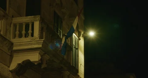 Building facade with balcony and flag illuminated at night Video stock 333778653