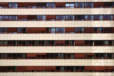 Building facade displaying rows of windows and red blinds Foto stock