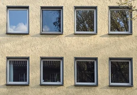 Building facade featuring multiple rectangular windows reflecting blue sk.. Stock Photos