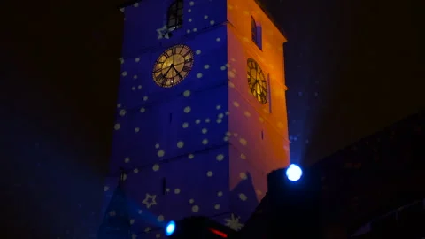 Building facade light show projecting stars onto a clock tower Stock Footage 334806408