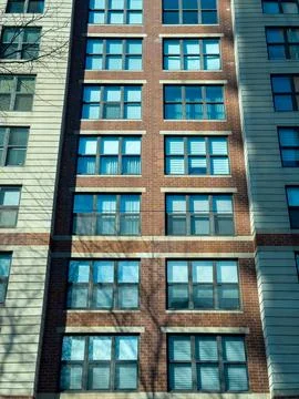 Building facade with multiple windows reflecting sunlight in a city setting.. Stock Photos