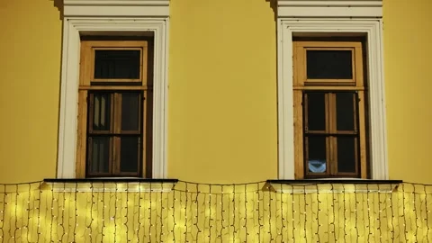Building facade at night with festive string lights decorating yellow wall and Stock Footage 335886913