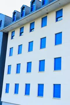 Building facade presenting a repeating pattern of white walls and bright bl.. 스톡 사진