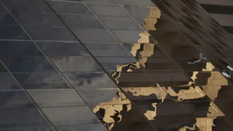 Building facade reflects clouds and sky in urban setting during daytime Stock Footage 343547588