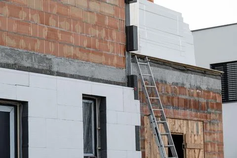 Building facade under construction is covered with insulation panels. The t.. Stock Photos