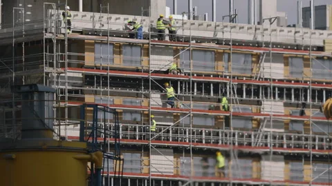 Building facade under construction with workers on scaffolding, daylight Vídeo Stock 333651853
