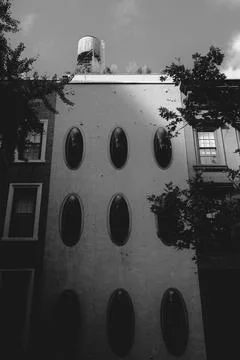 A building facade with unique oval windows and a rooftop water tower is see.. Stock Photos