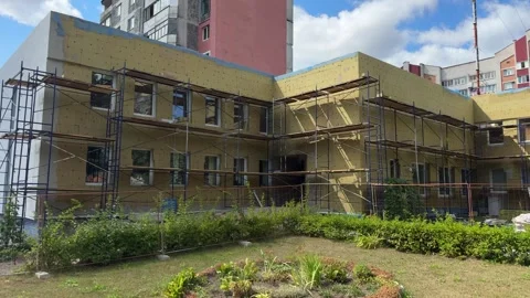 Building facade with yellow insulation panels and blue scaffolding  스톡 동영상 343408738