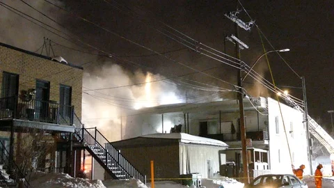 Building fire at night with firemen and power crews trying to shut off the power Stock Footage 104509348