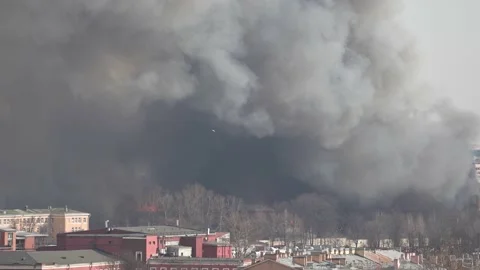 Building is on fire. Smoke. Flames behind the building. Roofs of houses in the Stock Footage 153411456