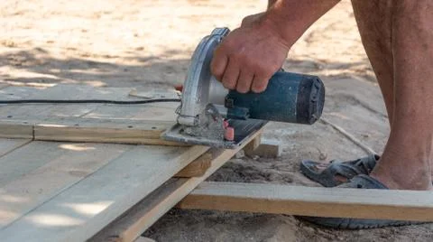 Building a formwork for the fence. Carpenter using a circular saw to cut a wo Stock Photos
