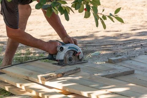 Building a formwork for the fence. Carpenter using a circular saw to cut a wo Stock Photos