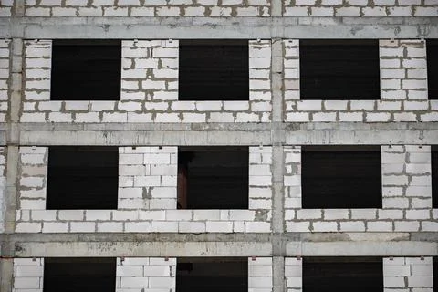 Building framework with white concrete blocks and dark empty window openings Stock Photos