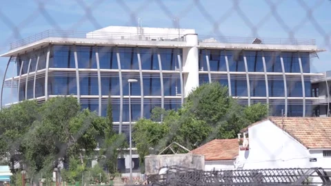 Building with glass facade partially built, viewed through fence Stock Footage 336558656