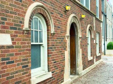 A building has several arched windows with a wooden door on a quiet street. T Stock Photos