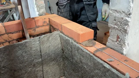 Building a heating stove, The bricklayer lays a brick on the reinforced lay.. Stock Footage 321840888