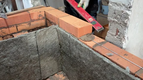 Building a heating stove, The bricklayer lays a brick on the reinforced lay.. Stock Footage 321840991