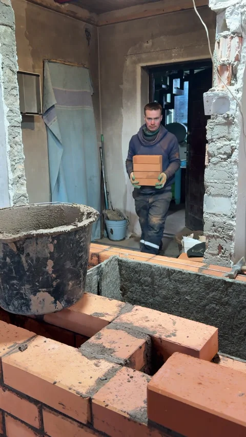Building a heating stove, Bricklayers assistant brings bricks to the masonr.. Stock Footage 321840643