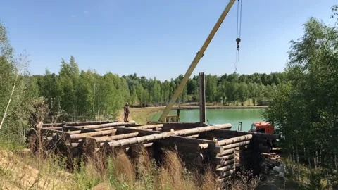 Building a house from a log. A group of men install a log house on a foundation. Stock Footage 131863480