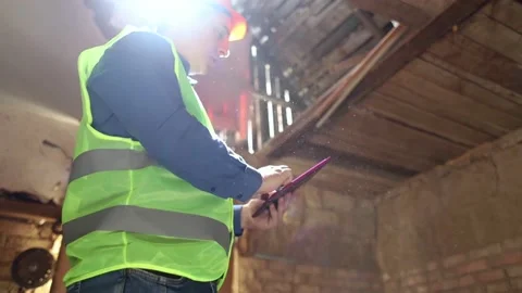 Building inspector. Man in a hard hat and a yellow reflective vest examines dama Stock Footage 205552121