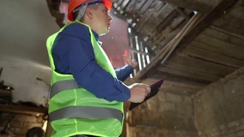 Building inspector. Man in a hard hat and a yellow reflective vest examines dama Stock Footage 205552186