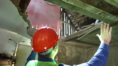 Building inspector. Man in a hard hat and a yellow reflective vest examines dama Stock Footage 205552231