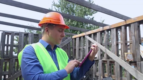 Building inspector. Man in a hard hat and a yellow reflective vest examines dama Stock Footage 205552267