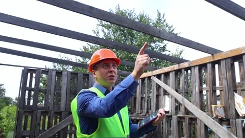 Building inspector. Man in a hard hat and a yellow reflective vest examines dama Stock Footage 205552269