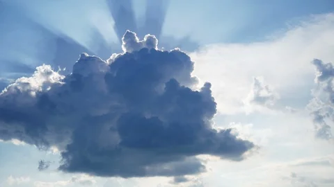 Building of a large white cloud in the blue sky, the sun's rays shine through Stock Footage 110750735
