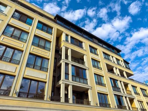 Building with large windows under a blue sky with clouds in an urban area d.. Stock Photos