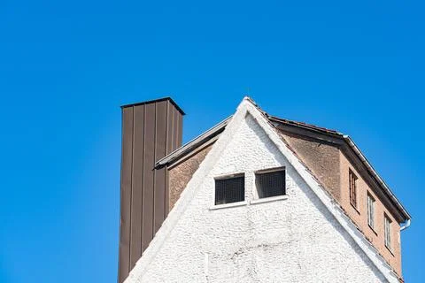 Building located under clear blue sky with chimney on rooftop Photos