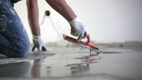 Building master in protective gloves pouring self-leveling screed on floor and Video stock 148791970