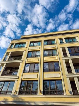 Building with multiple balconies under a blue sky with clouds in an urban s.. Stock Photos