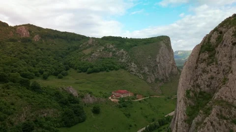 Building nestled among green mountain cliffs and sky Stock-Footage 345166321