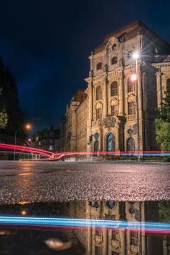 Building in the night with the reflection of a puddle. With light trails of Stock Photos