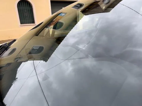 Building reflection and cloudy sky on car windshield Stock Photos