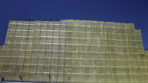Building renovation scaffolding mesh construction workers structure maintenance  Stock Footage 310052714