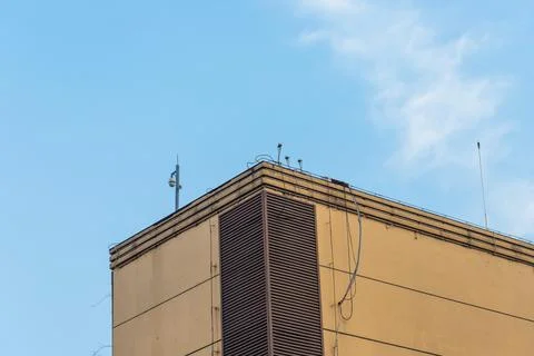 Building rooftop with security camera against blue sky Stock Photos