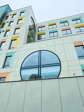 Building with round window and colorful design in urban area during overcas.. Stock Photos