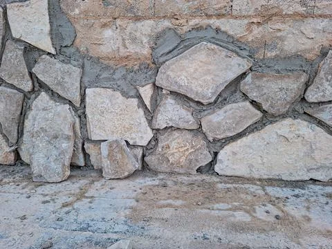 Building a rustic stone wall using beige limestone and grey cement mortar i.. Foto stock