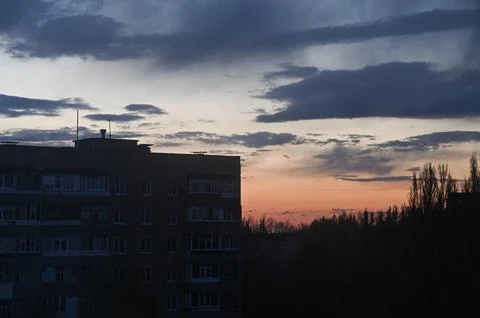 Building silhouette beneath dramatic sunset sky Stockfoto's