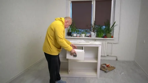 Building a simple white shelf unit in a cozy apartment with plants around Vídeos de archivo 326416622