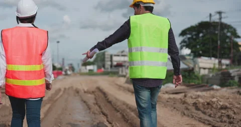 At a building site, a back-turned engineer and technician are walking around  Stock Footage 162997538
