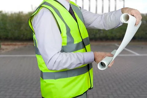 Building site engineer in high visibility vest checking technical drawing Stock Photos