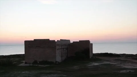Building on small island in water ocean off coast at sunset sunrise medium shot Stock Footage 252153446
