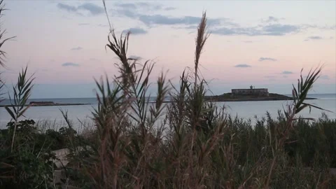 Building on small island in water ocean off coast at sunset sunrise wide shot Stock Footage 252153463