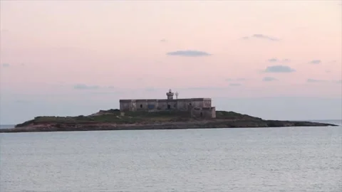 Building on small island in water ocean off coast at sunset sunrise medium wide Stock Footage 252153473