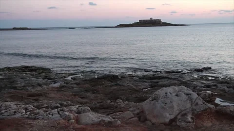 Building on small island in water ocean off coast at sunset sunrise wide shot Stock Footage 252153475