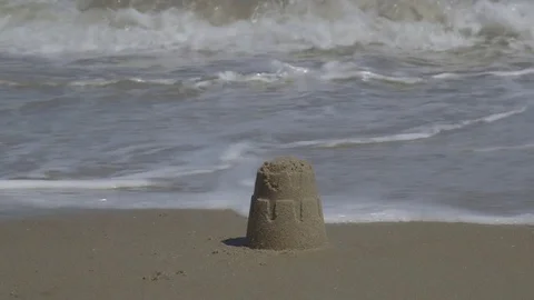 Building Small Sandcastles with Ocean Waves Crashing on the Beach Vídeo Stock 74369348
